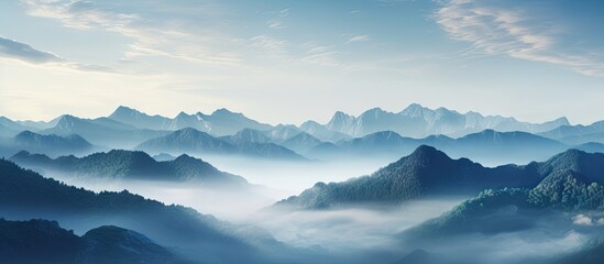Mountains wrapped in mist under a blue sky - obrazy, fototapety, plakaty