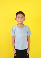 Portrait of smiling Asian boy age about 6 years old looking straight at camera isolated on yellow studio background. - 793797267