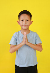 Portrait of Asian boy child age about 6 years old Pay respect or pray gesture isolated on yellow background. - 793797471