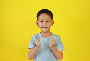 Asian boy child show finger mini heart symbol sign language isolated on yellow studio background.