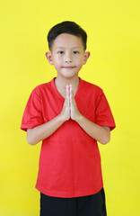 Portrait of Asian boy age about 6 years old Pay respect gesture and looking straight at camera...