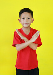 Asian boy child in red casual age 7 years old crossed his hands gesture isolated on yellow background. Happy child show stop sign or making X sign arms and looking camera. - 793797833
