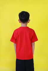 Rear view of Asian boy age 6 year old isolated on yellow background. - 793797885