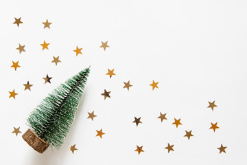 new year background with christmas tree and star confetti on a light white background. Festive xmas decoration gold stars confetti. Empty space for copy space. flat lay, top view
