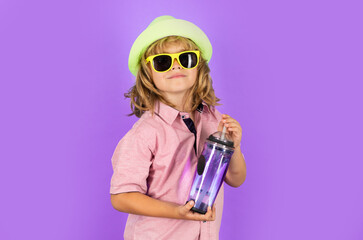 Kid drinking water, isolated on studio background. Portrait of happy smiling little child with glass of fresh water. Thirsty kid. Refreshing. Water balance. Portrait of kid drinking pure still water.