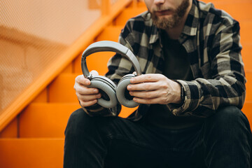 Professional gray headphones in the hands of a man, close-up.