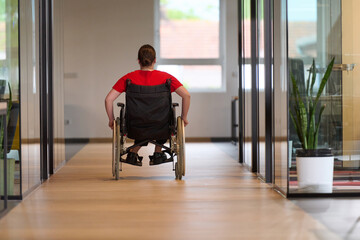 A modern young businesswoman in a wheelchair is surrounded by an inclusive workspace with...