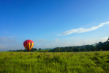 Bunter Heißluftballon gelandet auf freiem Feld bei Sonnenschein 