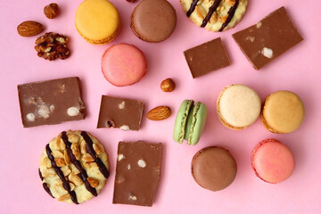 Pastel macarons, almond chocolate, peanut butter cookies and various nuts on bright pink...