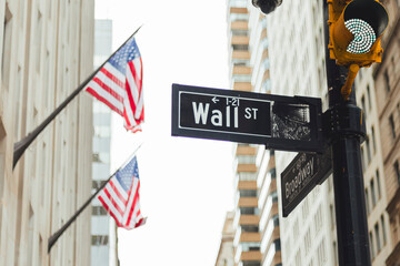 Wall street sign with American flag behind.