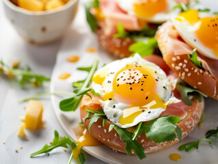 Obraz premium Oriental bagel with feta cheese, eggs, arugula and sea salt on a white plate over a light background. Healthy breackfast.