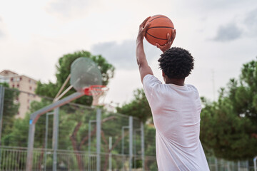 young black man shooting basket. unrecognizable young athlete playing basketball.