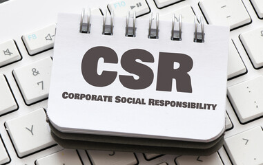 Corporate Social Responsibility (CSR) words in an office notebook. view from above.