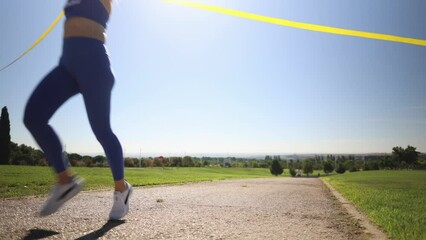 senior woman marathon runner, with bib number, wins the race and celebrates it at the finish line