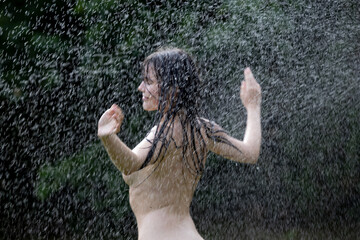 Beautiful woman enjoying under a water jet with thousands of drops in the background