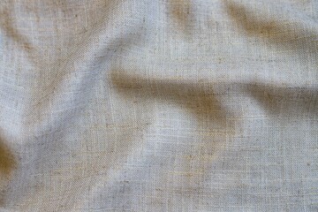 Beige linen fabric texture with folds. Close up.