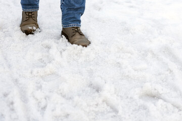 a man in boots walks through melted snow