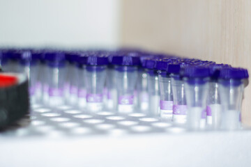 Test tubes with violet lids arranged on a laboratory shelf