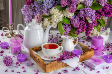 A table with a tea set, candles, and flowers.