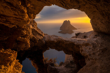 Es Vedra islet view through the rock holes of a cave at sunset, Sant Josep de Sa Talaia, Ibiza, Balearic Islands, Spain