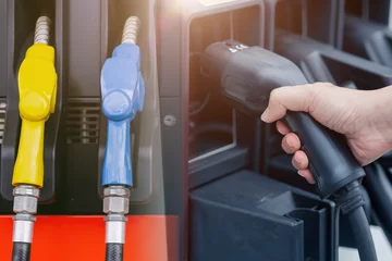 Tuinposter Duel energy vehicle alternative type compare EV charging station electricity car with old fuel nozzle at gas station © Quality Stock Arts