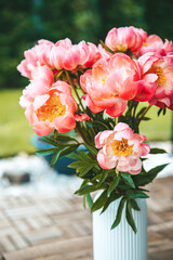 Lush pink peonies fill a white vase with vertical ridging, creating a vibrant display