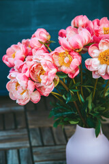 A bouquet of pink peonies, with their vibrant pink petals, are fresh and blooming, showcasing their full blossoms. The bouquet is housed in a ribbed pink vase.