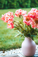 A bouquet of pink peonies, looking fresh and full of life. They are housed in a pink ribbed vase