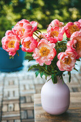 Lush pink peonies fill a pink vase with vertical ridging, creating a vibrant display