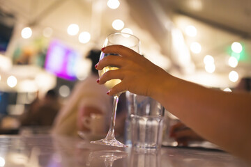 Woman's hand takes a glass ow white wine in restaurant