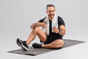 Man Resting on a Fitness Mat, Using Phone
