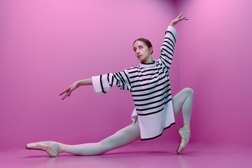 young ballerina in white tights and a half-skirt poses ballet steps standing on pointe shoes