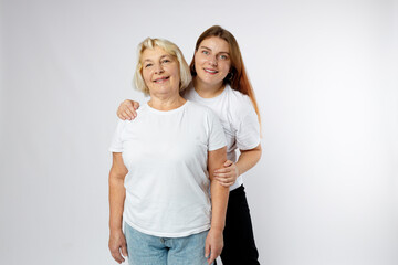 Head shot portrait of happy senior 60s mother and young grownup daughter over white studio background. Family day concept.