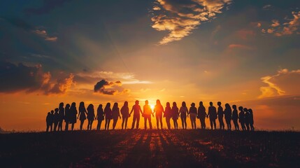 A group of women holding hands in front of a sunset.