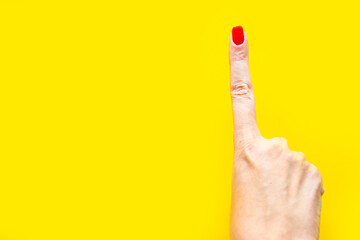 Woman's hand shows the point gesture over bright yellow background. Minimal concept. Copy space for...