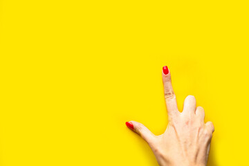 Woman's hand shows the point gesture over bright yellow background. Minimal concept. Copy space for the text