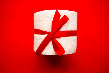 toilet paper roll wrapped in gift bow on red background. Covid19 concept