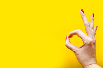 Woman's hand shows the OK gesture over bright yellow background. Minimal concept. Copy space for the text