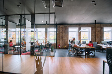 A diverse group of business professionals collaborates in a modern startup coworking center,...