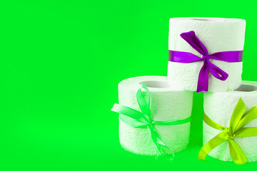 toilet paper rolls wrapped in gift bows on bright green background. Covid19 concept. Copy space for the text