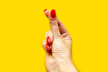 Closeup view of female hand forming gesture money. Isolated on bright yellow background.