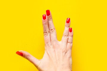 Closeup view of female hand forming gesture two fingers UFO. Isolated on bright yellow background.