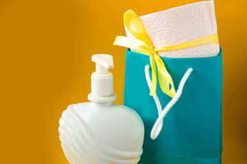 Toilet paper roll with gift bow and liquid soap on bright yellow background. Covid19 concept. Quarantine concept