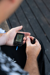 Men check their sugar levels using a lancet pen and glucometer