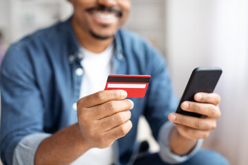 African american man holding credit card and phone