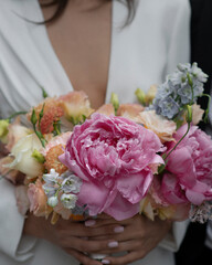 A woman's hands emerge from a vibrant bouquet of pastel blue and pink flowers
