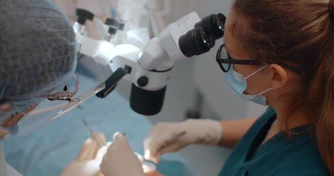 Portrait of the dental surgeon using the microscope during the surgery in dental clinic