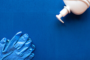 Liquid soap and medical gloves on blue background. Copy space for the text. Coronavirus concept