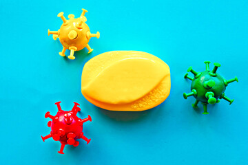 Bright yellow soap bar and viruses on blue background. Covid-19 concept