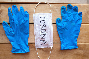 Medical gloves and mask with word Corona on wooden background. Covid-19 concept